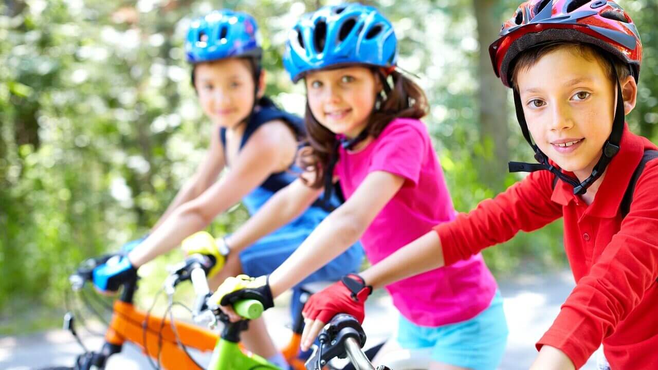 3 smiling children cycling